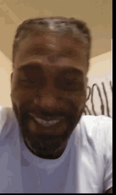 a man with a beard wearing a white shirt smiles