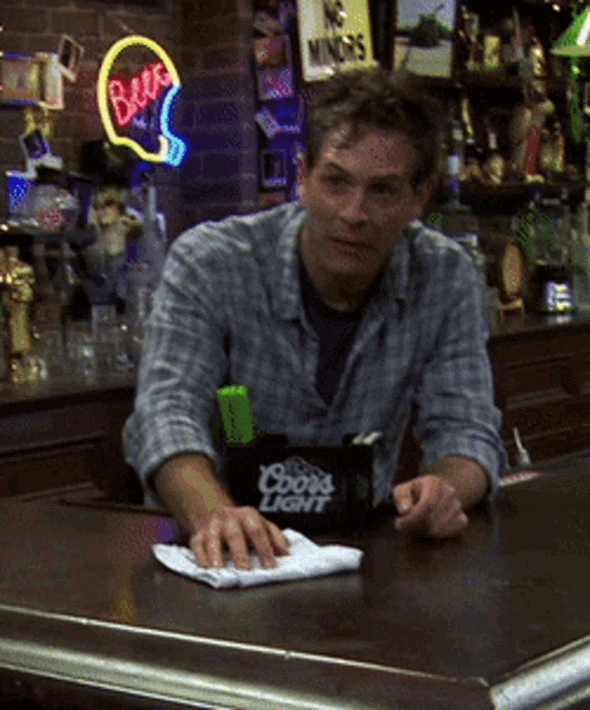 a man sitting at a bar with a coors light container on the counter
