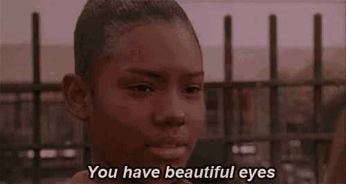a girl is standing in front of a fence with the words `` you have beautiful eyes '' written on her face .