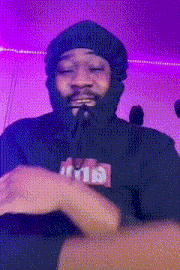 a man wearing a beanie and a black hoodie is making a funny face .