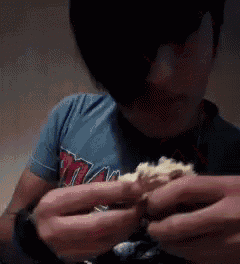 a person wearing a miami shirt is eating a sandwich