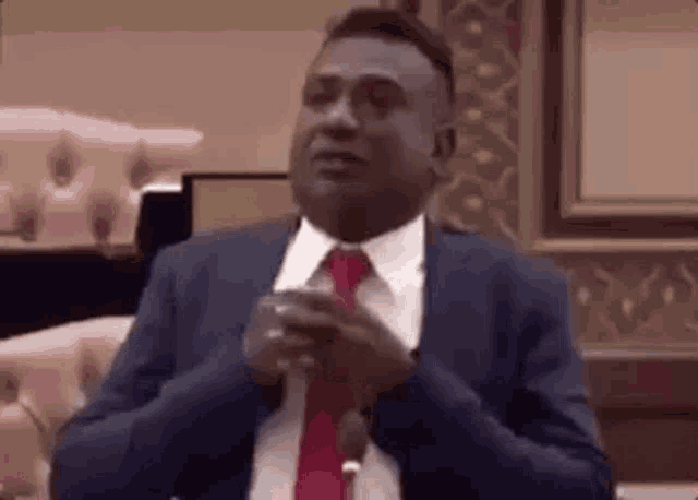 a man in a suit and tie is clapping his hands .