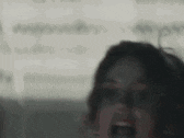 a woman is screaming with her mouth open in a blurry photo .