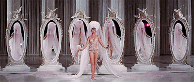 a woman is standing in front of a row of mirrors on a stage