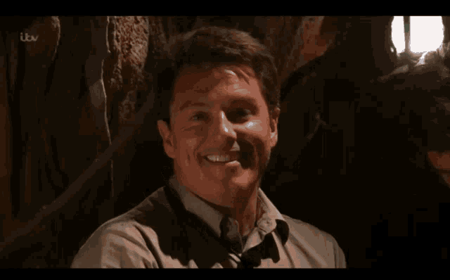 a man is smiling in front of a tv screen