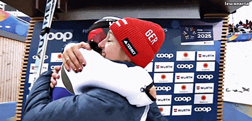 a man in a red hat with the word ger on it hugging another man