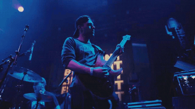 a man playing a guitar on a stage with a sign that says bebel