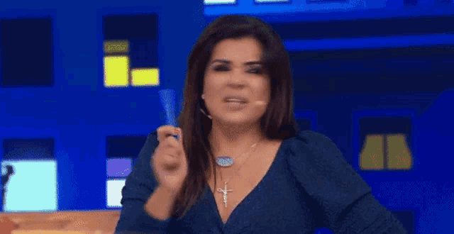 a woman in a blue dress is standing in front of a blue background holding a microphone .