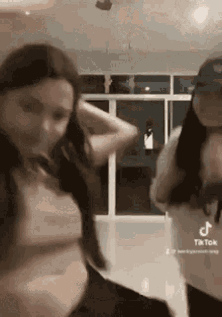 a couple of women are dancing together in a room in front of a window .
