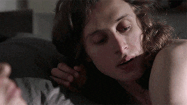 a woman with long hair is laying on a bed with a man