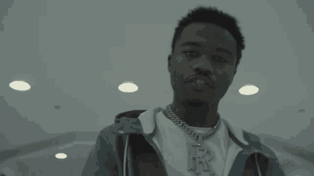 a man with a chain around his neck is giving the middle finger to the camera