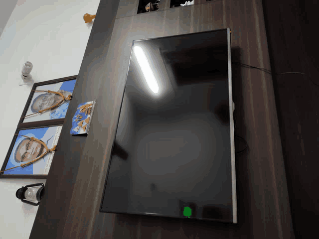 a flat screen tv is hanging on a wall next to a picture of a man
