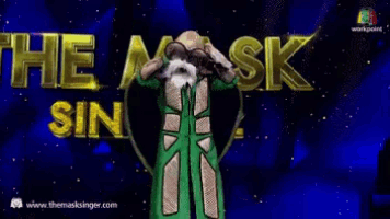 a woman in a green suit is standing in front of a sign that says e mask show