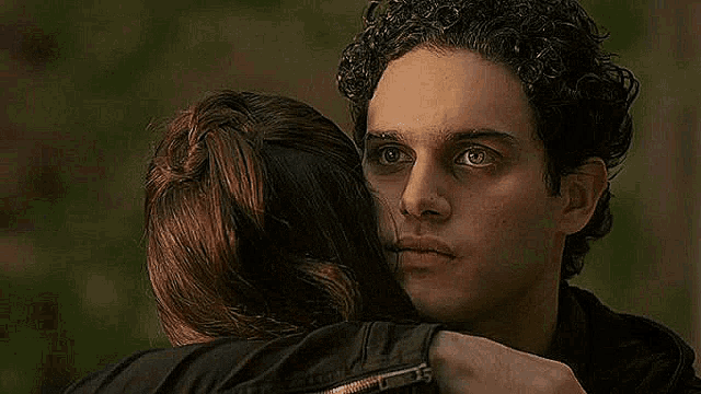 a man and a woman are hugging each other and the man is looking at the camera .