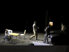 a group of people standing around a table and chairs on a stage