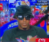 a man wearing a hat and sunglasses is on a tv screen with the time 7:57 pm pt