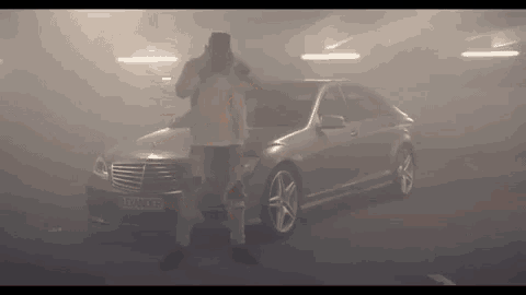 a man is standing in front of a mercedes with a license plate that says danger