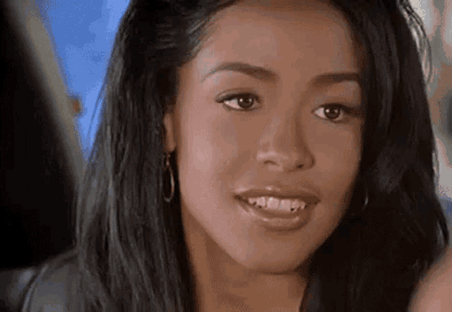 a close up of a woman 's face with long black hair and earrings .
