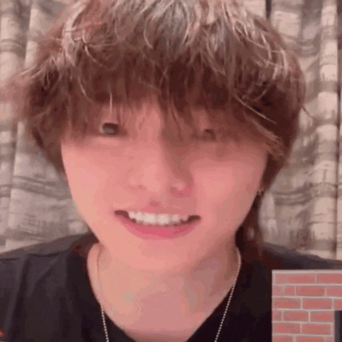 a close up of a person 's face with a brick wall behind them .