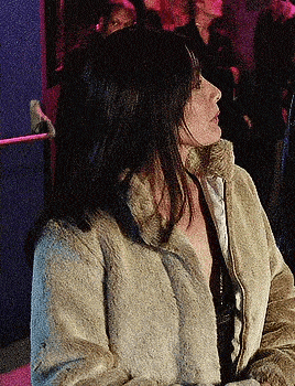 a woman is wearing a fur coat and looking to the side