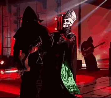 a man in a skeleton costume is dancing on a stage while a man playing a guitar .