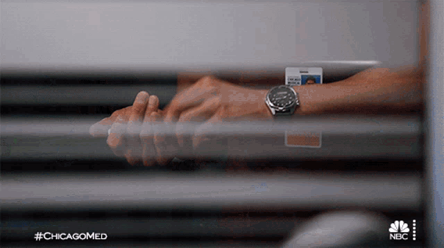 a man wearing a watch is behind a window with #chicagomed on the bottom