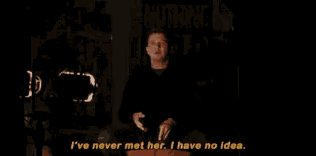 a man is sitting in a dark room talking to a woman .