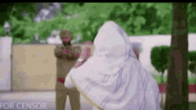 a woman in a white veil is standing in front of a police officer in a park .
