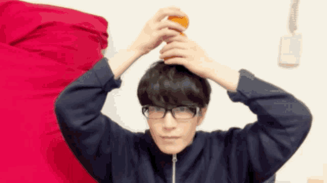 a man wearing glasses is holding a cup on his head .