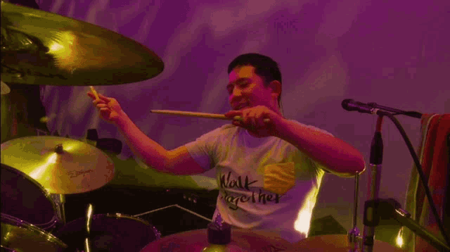 a man playing drums wearing a shirt that says " walk together "