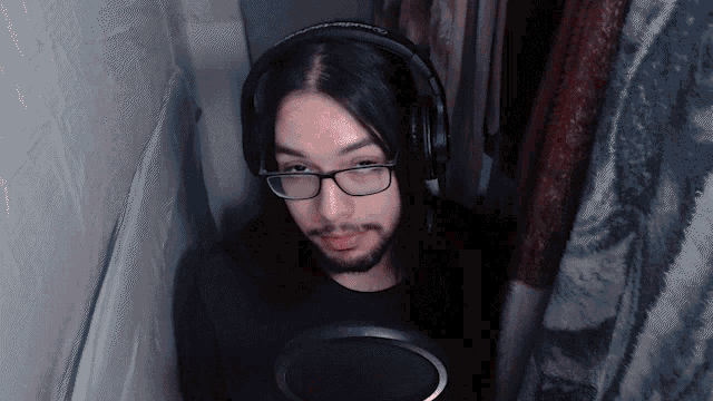 a man with long hair and glasses is wearing headphones and a black shirt