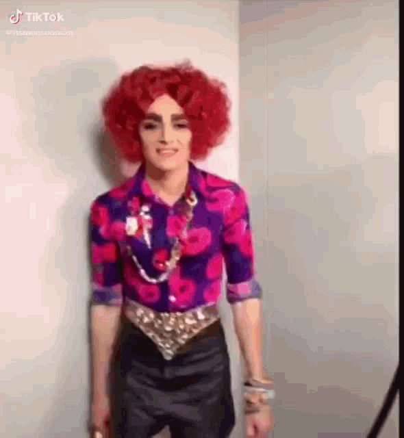 a man with red hair is wearing a wig and a purple shirt .