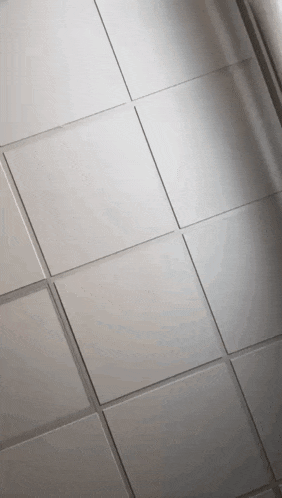 a close up of a tiled ceiling with a shadow on it