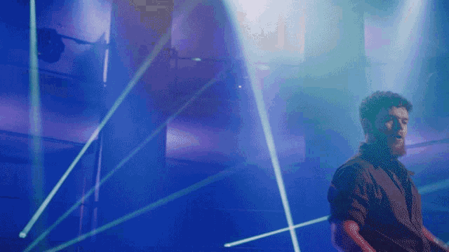 a man in a black shirt is standing in front of blue lights