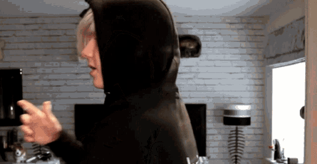 a person wearing a black hoodie is standing in a living room