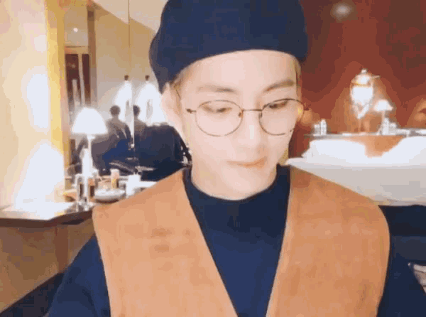 a man wearing glasses and a hat is standing in a room