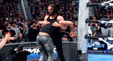 a wrestler is hugging another wrestler in front of a crowd with a sign that says prime