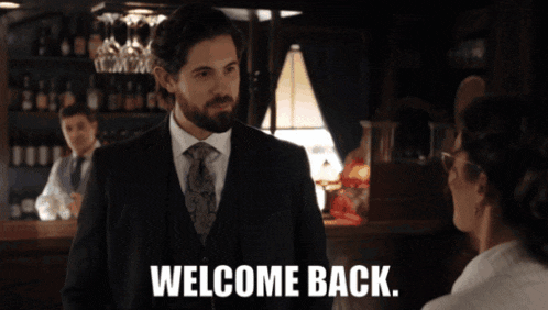 a man in a suit and tie is standing in front of a woman with the words welcome back on the bottom