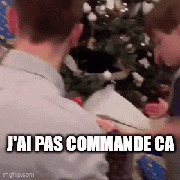 a man is sitting in front of a christmas tree holding a gift box .