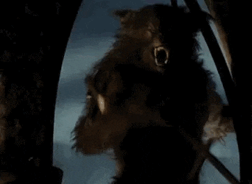 a werewolf is standing in front of a stone wall in a dark room with its mouth open .
