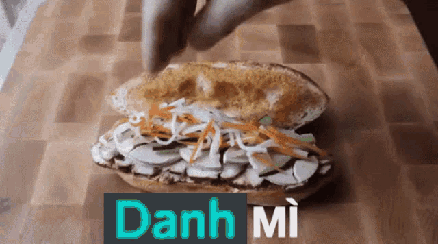 a close up of a sandwich on a wooden cutting board with the word danh mi in the corner