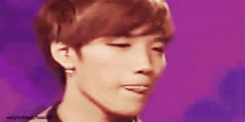 a close up of a young man 's face with his tongue sticking out against a purple background .