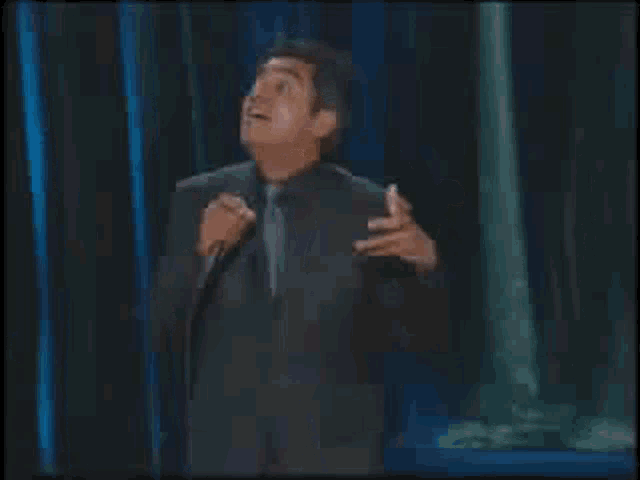 a man in a suit is singing into a microphone .