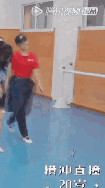 a woman in a red shirt is dancing on a blue floor in a dance studio ..