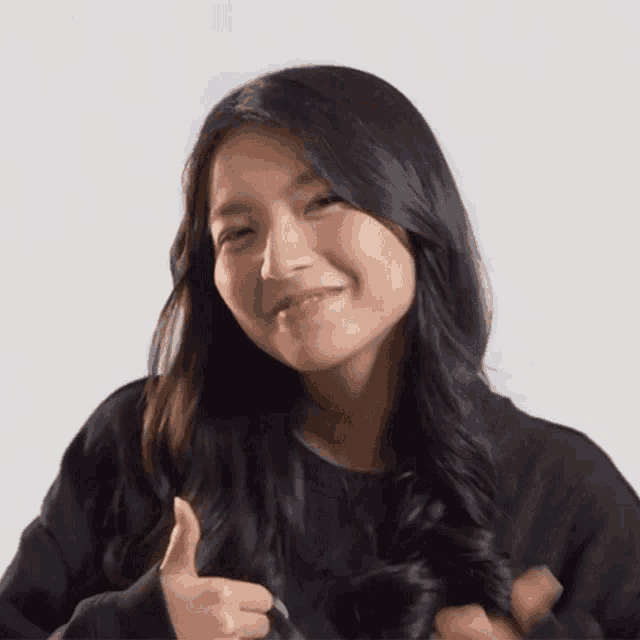 a woman with long black hair is giving a thumbs up sign