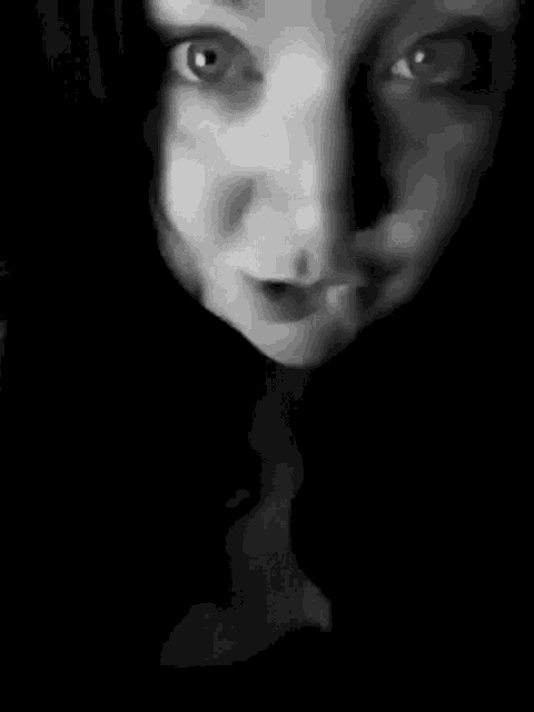 a black and white photo of a woman 's face with her mouth open .