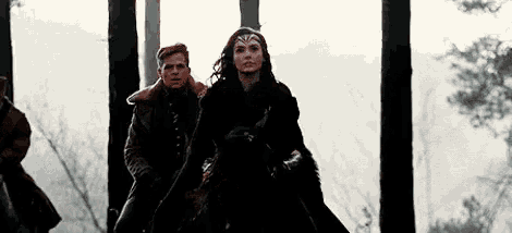 a man and a woman are standing in the woods .