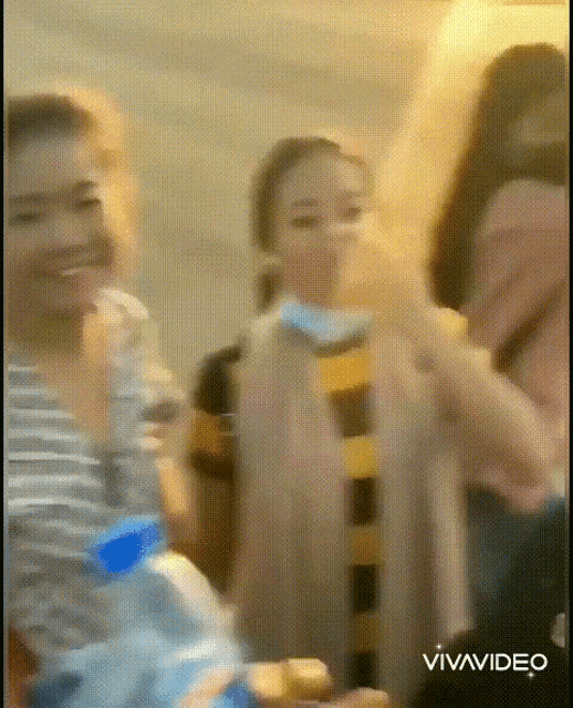 a group of people are standing in a room with a bottle of water in the foreground
