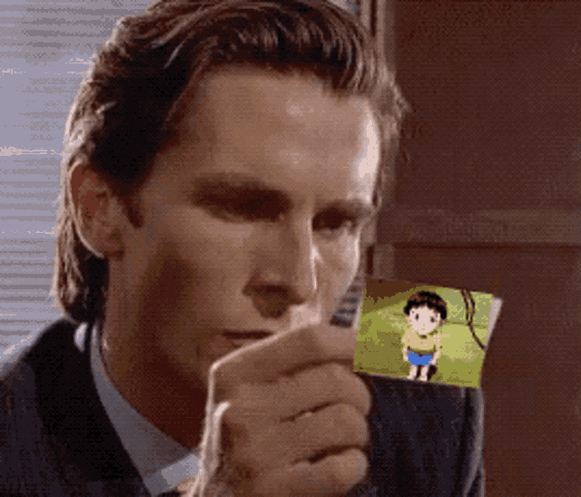 a man in a suit is holding a picture of a boy in a yellow shirt