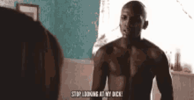 a shirtless man is standing in front of a mirror and talking to another man .
